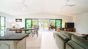 A modern interior with a dining area, a sofa, and a television. - Beachside on Pacific (Mission Beach)