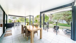 Eine großzügige Terrasse mit Esstisch und Stühlen, einem Grill und Blick auf einen üppigen Garten.