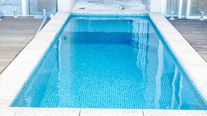 A rectangular swimming pool with a tiled edge, surrounded by a white border. - Doorilla Coastal Retreat (Mission Beach)
