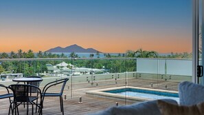 A rooftop pool with a view of a mountain and palm trees.