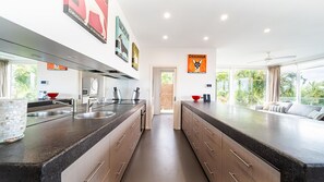 A modern kitchen with a central island, stainless steel appliances, and a view to the outside.