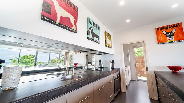 A modern kitchen with a large island, stainless steel appliances, and artwork on the walls.
