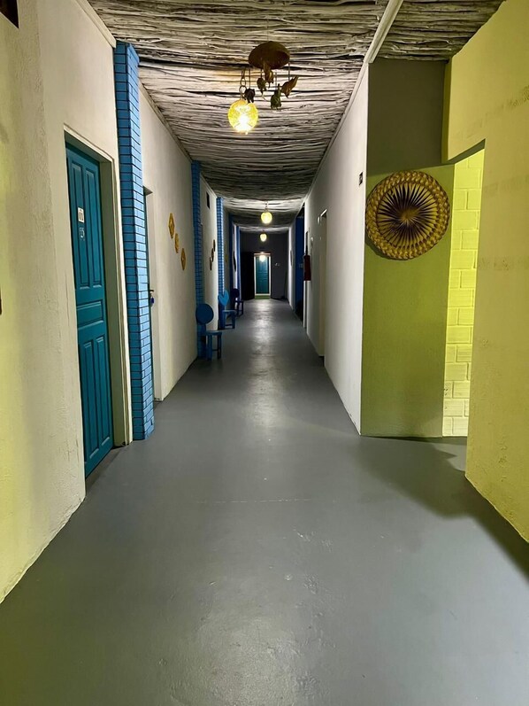 A narrow hallway with blue and yellow walls, a patterned ceiling, and a door with a circular design on the right.