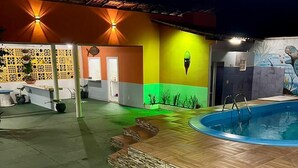 A pool area with a wooden deck, a small pool, and a colorful wall with a mural. - Pousada Toa Toa Maruda (Marapanim)
