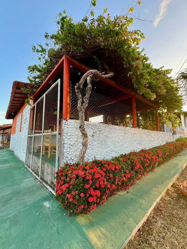 Um edifício com fachada de pedra, um alpendre coberto e um canteiro de flores vermelho.