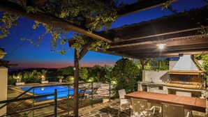 Eine Außenpatio mit Pool, Grillbereich und Sitzgelegenheiten.