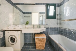 Ein modernes Badezimmer mit Waschmaschine, Waschbecken und Badewanne.