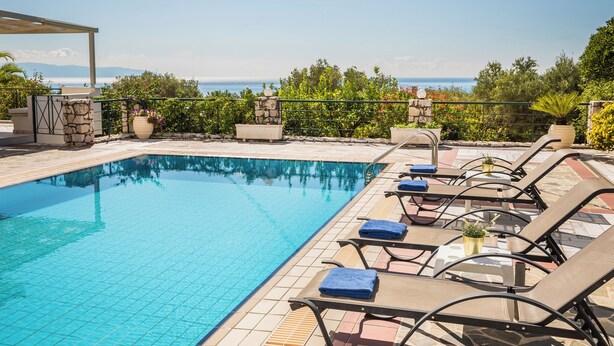 Ein Pool mit Liegestühlen und einer Steinmauer.