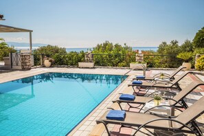 Une piscine avec des chaises longues et un mur en pierre.