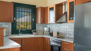 Eine moderne Küche mit Holzschränken, einem Edelstahlkühlschrank, einem Einbauofen und einer Kaffeemaschine.