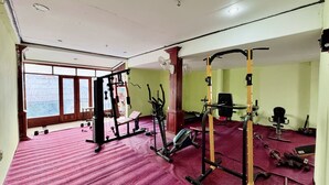 A gym with various exercise equipment, a red carpet, and large windows. - Paradise Hostel  (Vang Vieng)