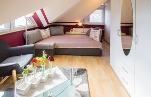 A compact room with a bed, a chair, a table with vases, and a window. - Apartment 'Hornisgrindeblick' with Mountain View, Balcony and Wi-Fi (Renchen)