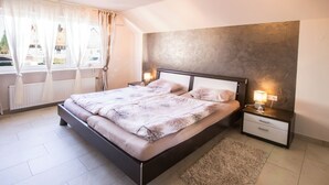 Een moderne slaapkamer met een groot bed, nachtkastjes, een raam met gordijnen en een structuurwand.