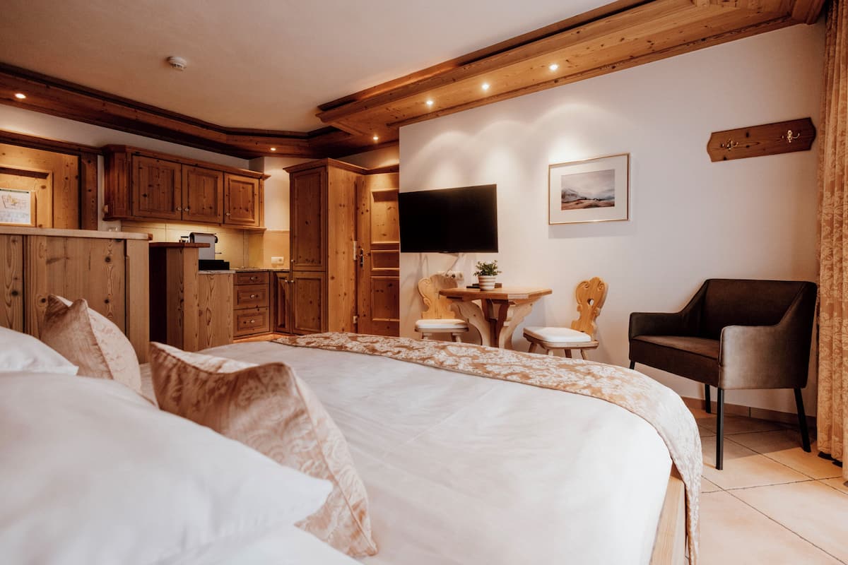 Un dormitorio con una cama grande, armarios de madera, un televisor y una silla.