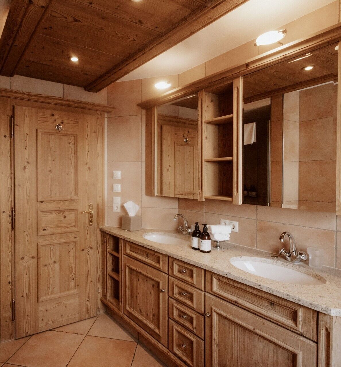 A wooden bathroom with two sinks, a large mirror, and wooden cabinets.