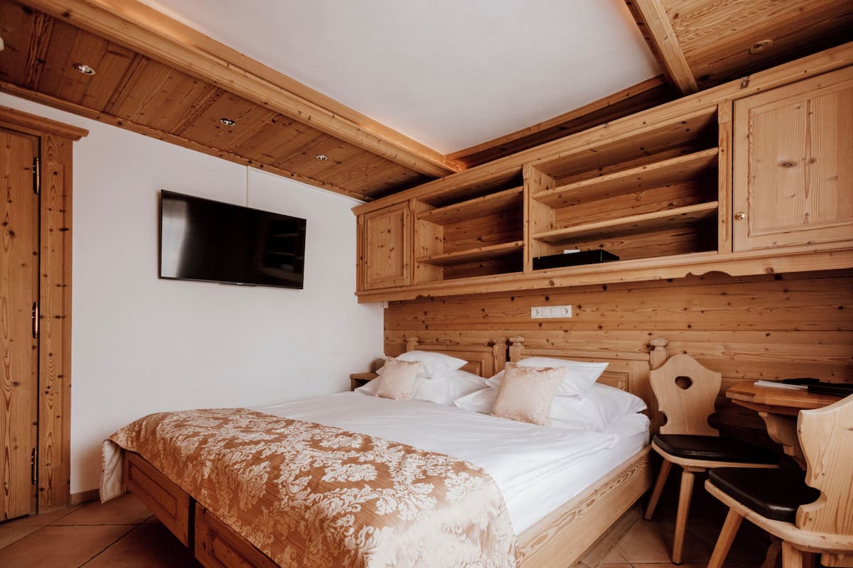 Un dormitorio de madera con una cama, un televisor y estanterías empotradas.