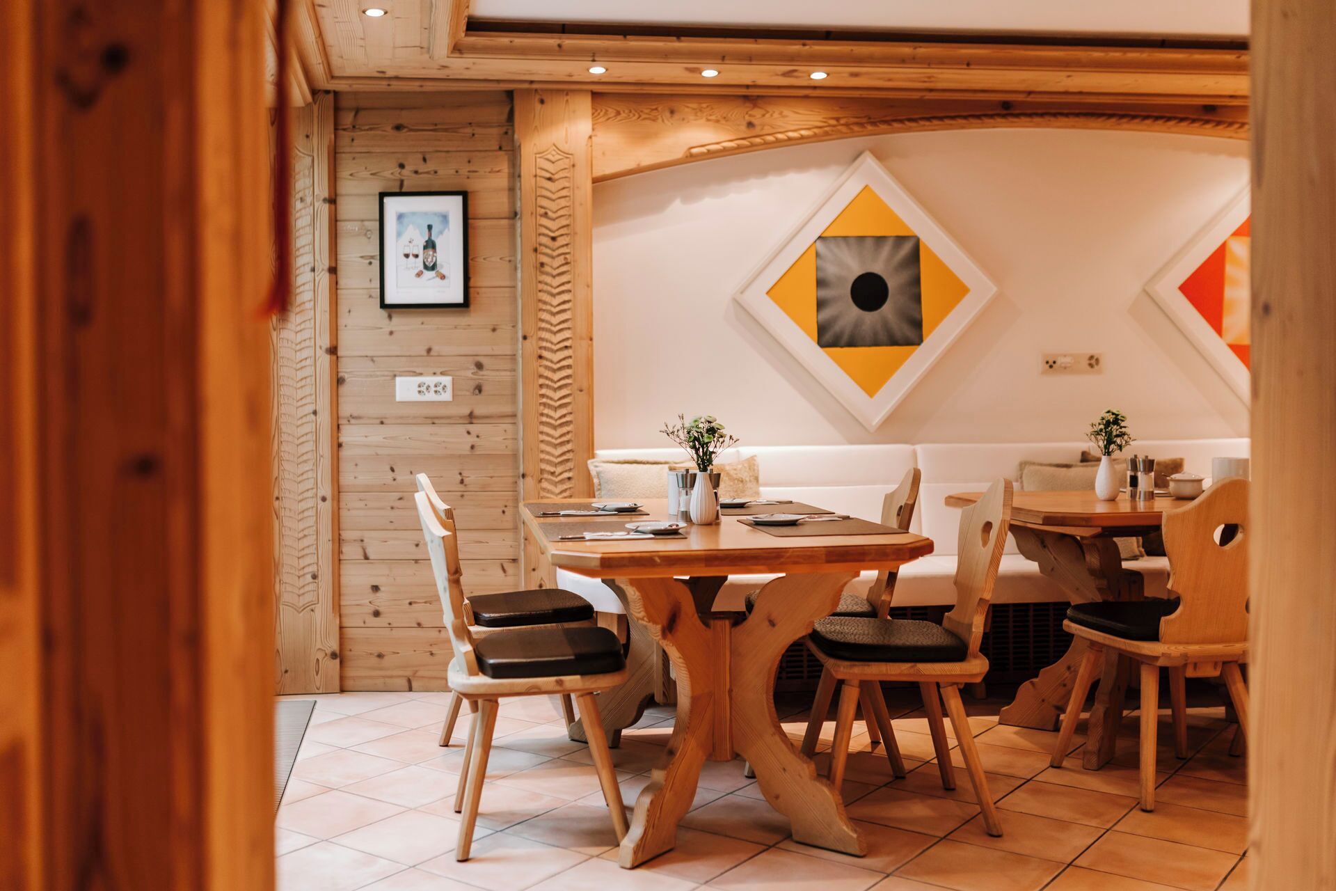 A dining area with a wooden table and chairs, a white sofa, and a wall with framed artwork.