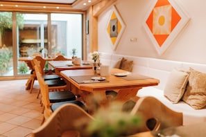 Un comedor con mobiliario de madera, un sofá blanco y un ventanal grande.