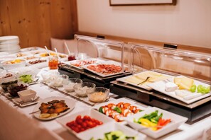 Ein Buffet mit verschiedenen Speisen, darunter Fleisch, Käse und Gemüse.