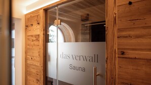 Een houten deur met een geëtste ruit waarop 'das verwall Sauna' staat.