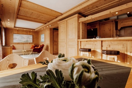 A wooden interior with a dining table, chairs, and a kitchen area.. Das Verwall Finest Apartments