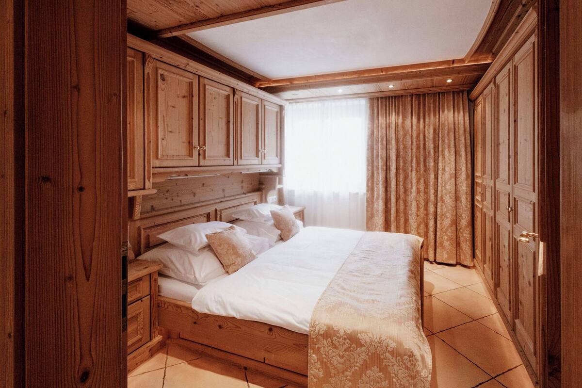 Un dormitorio de madera con cama, cortinas y ventana.