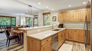 Una cocina moderna con armarios de madera, un refrigerador de acero inoxidable y una isla grande con un lavamanos.