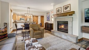 Una sala moderna con chimenea, un comedor y una cocina al fondo.