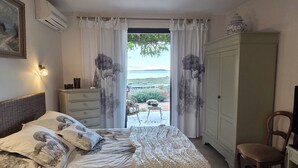 A bedroom with a bed, a chair, a wardrobe, and a view of the outdoors. - La Maison du pêcheur with garden, spa and pool facing the south-facing pond (Bages)