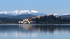 A lakeside town with buildings on a hillside, reflecting on calm water. - La Maison du pêcheur with garden, spa and pool facing the south-facing pond (Bages)