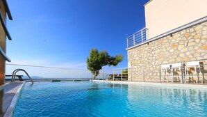 A clear blue pool with a stone wall and a metal railing. - Hill Suites (Vlore)