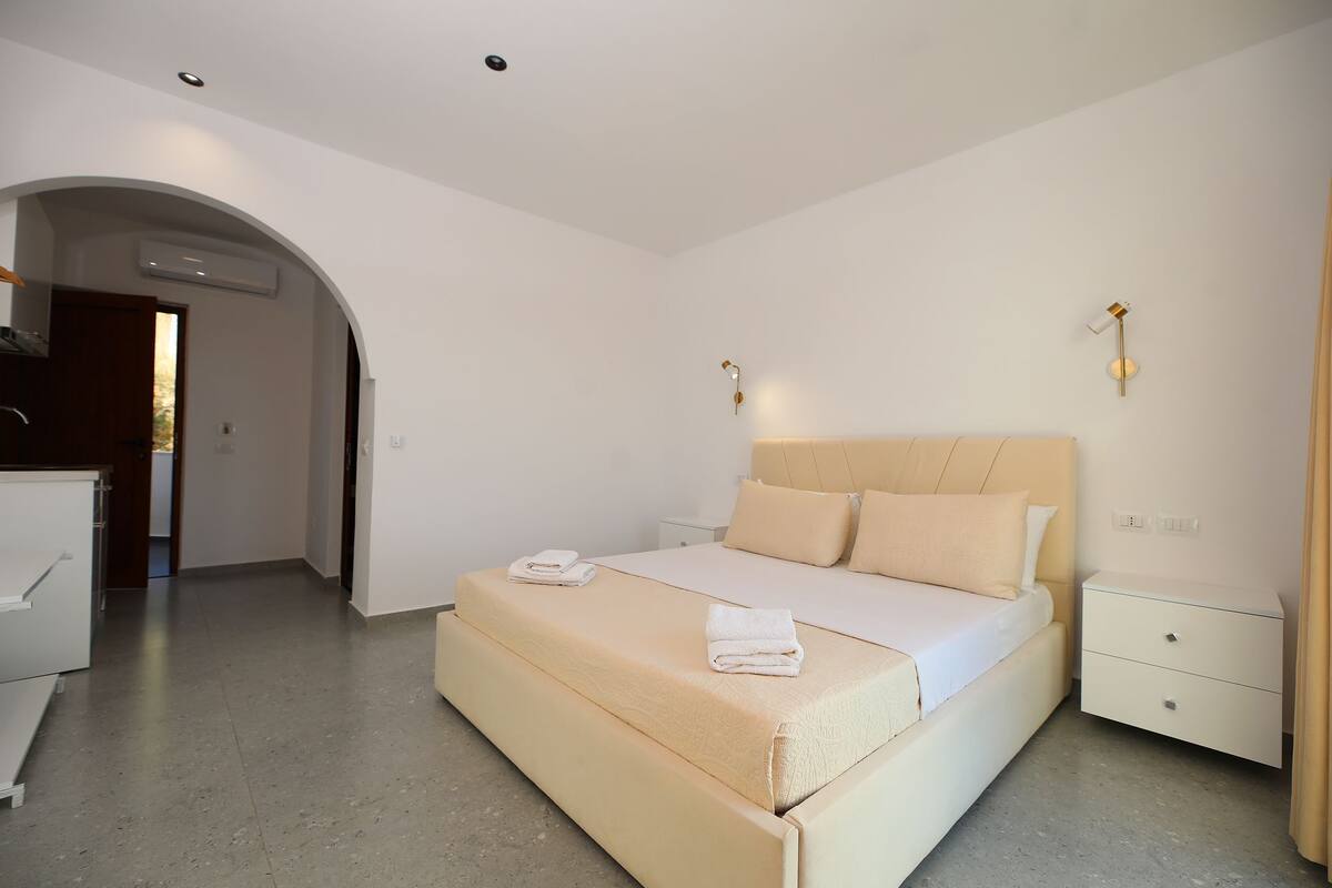 Quarto com cama, mesas de cabeceira e uma porta em arco.