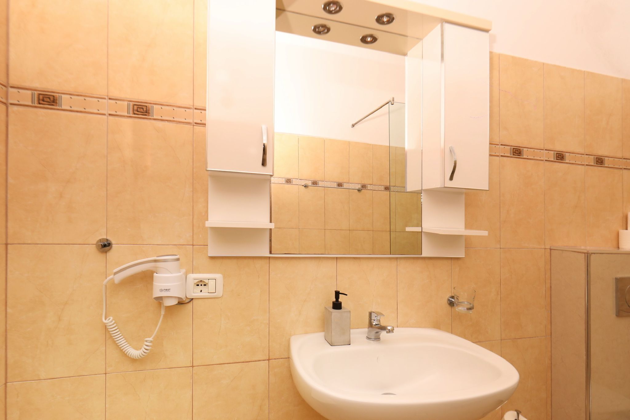 A bathroom with a white sink, a mirror above it, and a telephone mounted on the wall.