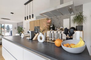 A modern kitchen with a large island, stainless steel appliances, and a variety of kitchenware.