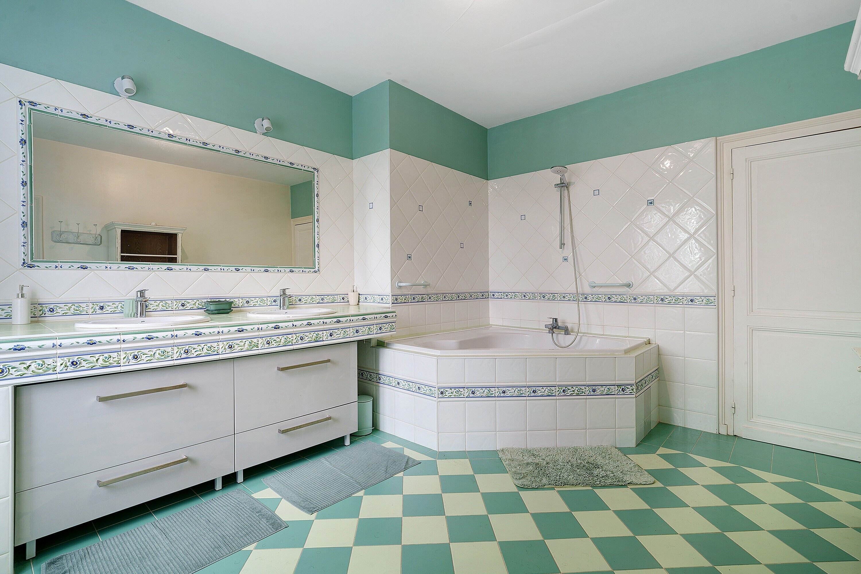 A bathroom with a white vanity, a large mirror, a bathtub, and a shower.