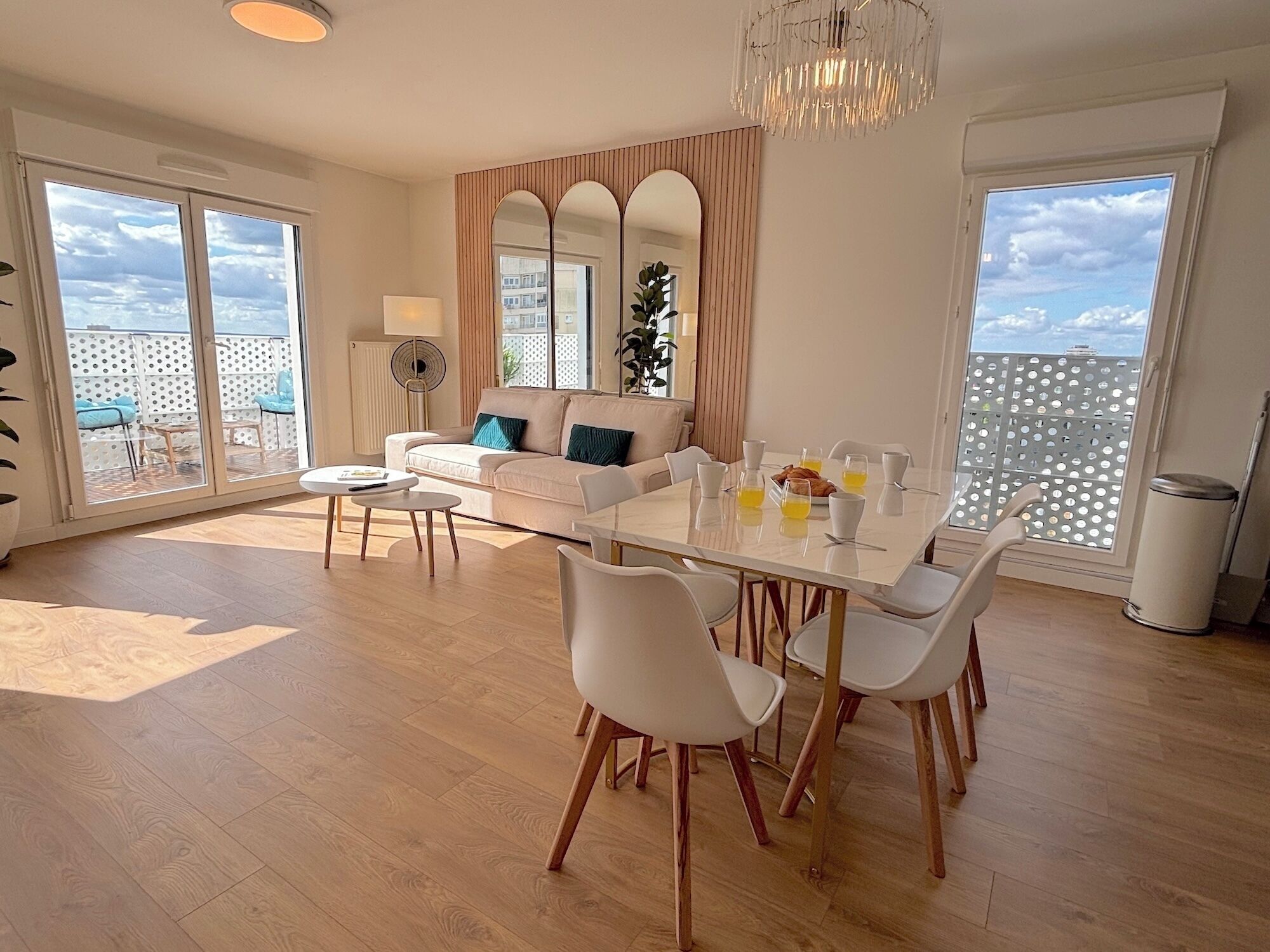 Een moderne eethoek met een witte tafel en stoelen, een bank en een grote spiegel.