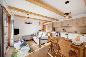 A modern kitchen with wooden cabinets, a dining table, and a built-in oven. - Holiday Apartment 'Holzfäller' with Private Terrace, Shared Garden and Wi-Fi (Lenzkirch)