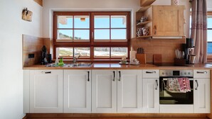A kitchen with white cabinets, a wooden countertop, a window with a view, and a built-in oven. - Apartment 'Hirtebube' with Shared Garden, Balcony, and Wi-Fi (Lenzkirch)