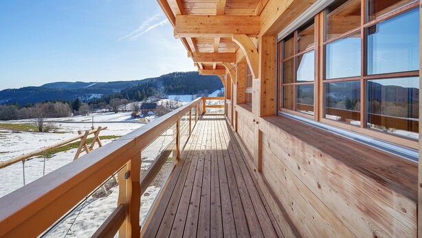 A wooden deck with a view of a snowy landscape and mountains. - Apartment 'Hirtebube' with Shared Garden, Balcony, and Wi-Fi (Lenzkirch)