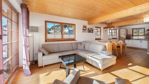 Una sala de estar moderna con un sofá seccional, una mesa de centro de vidrio y un comedor con una mesa y sillas de madera.