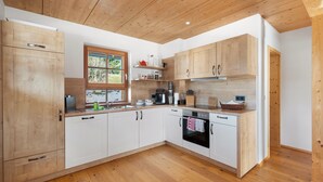 Una cocina moderna con armarios de madera, horno empotrado y ventana con vista a la vegetación.