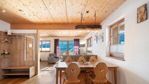 Comedor de madera con una mesa, sillas y un banco, y vista al exterior.