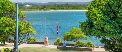 A coastal view with a lighthouse, beach, and greenery.