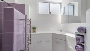 Ein modernes Badezimmer mit Dusche, Waschbecken und Spiegel.