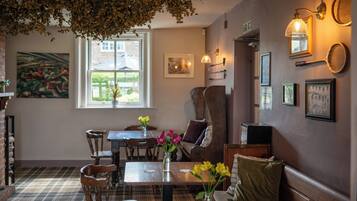 A cozy room with a plaid floor, wooden furniture, a window with a view, and wall-mounted lights.