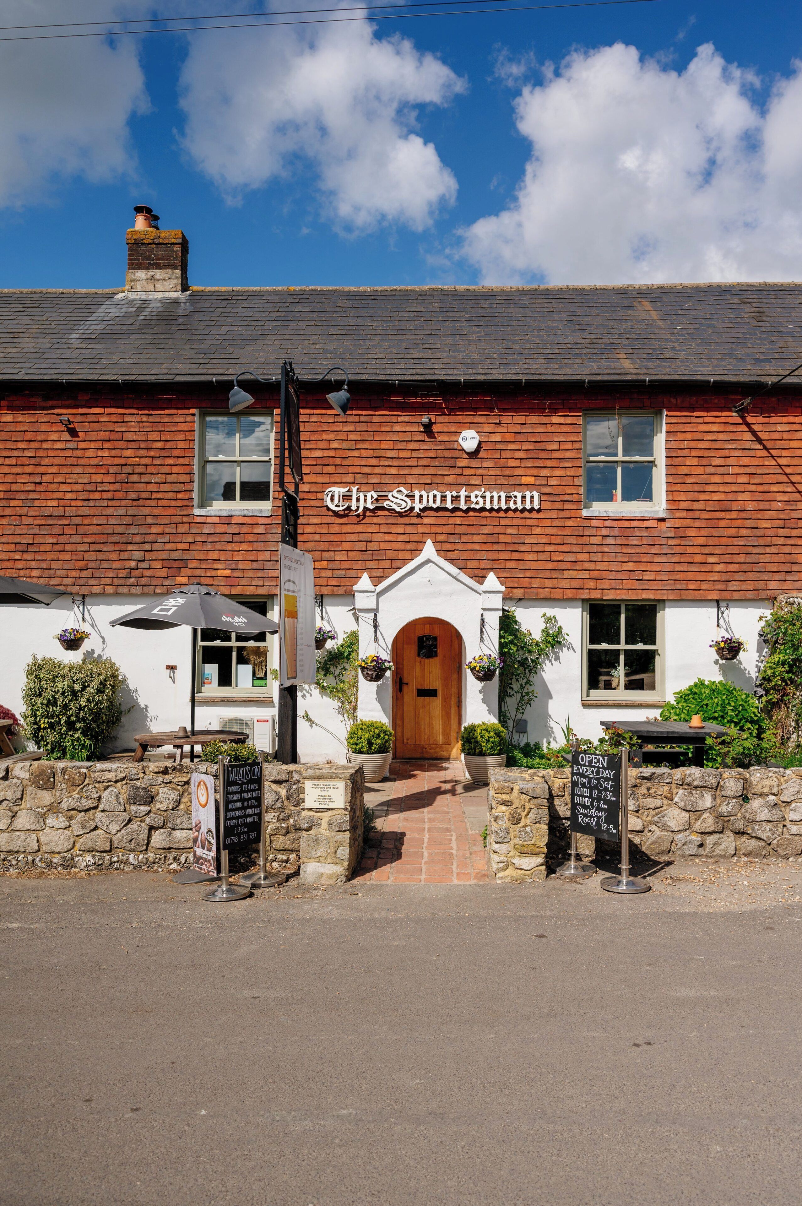 A traditional brick building with a wooden door and a sign reading 'The Sportsman.'