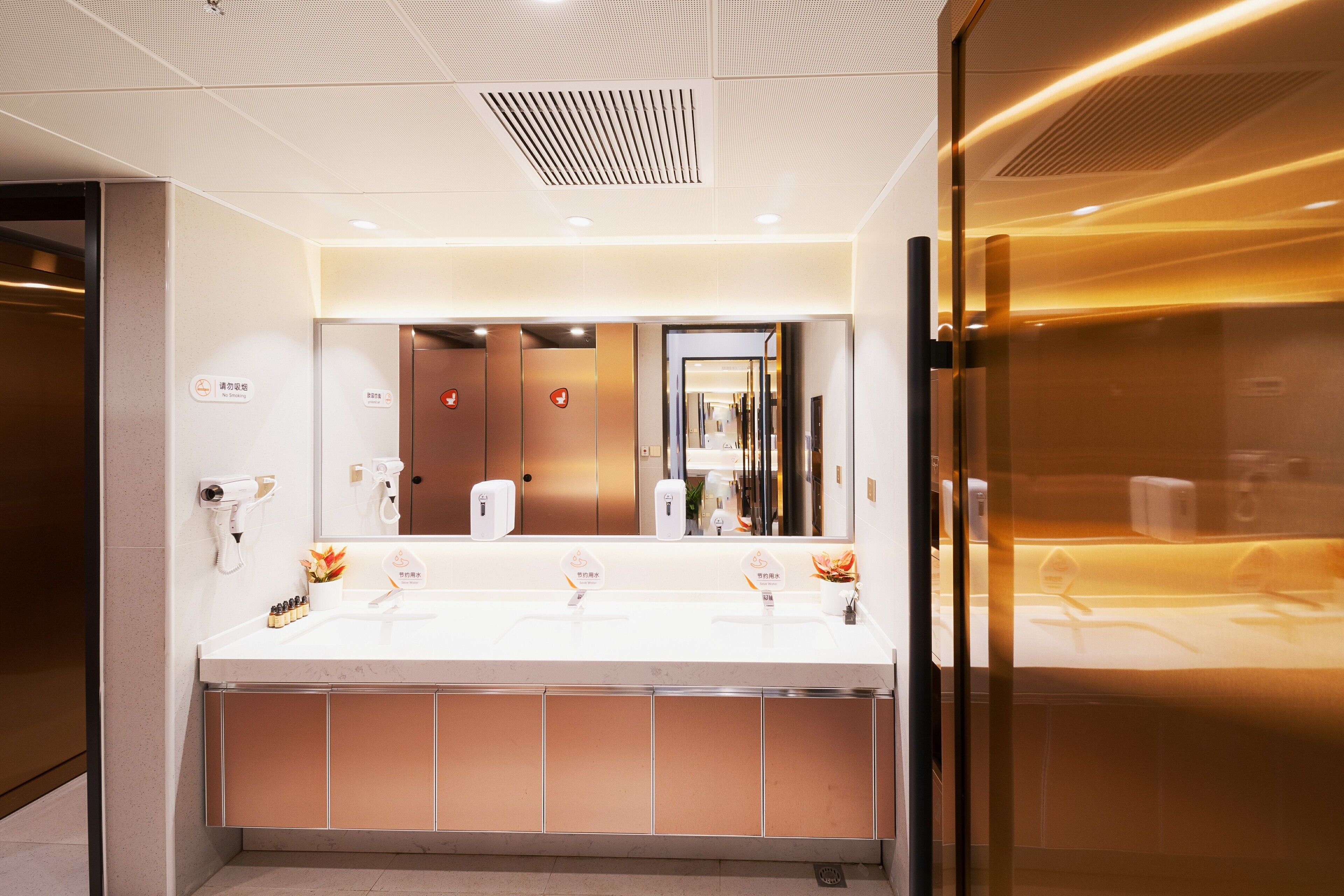 A modern bathroom with a large sink, hand dryers, and a mirror.