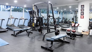 A gym with treadmills, weight machines, and benches. - Stylish 2BR Business Bay Pool Access (Dubai)