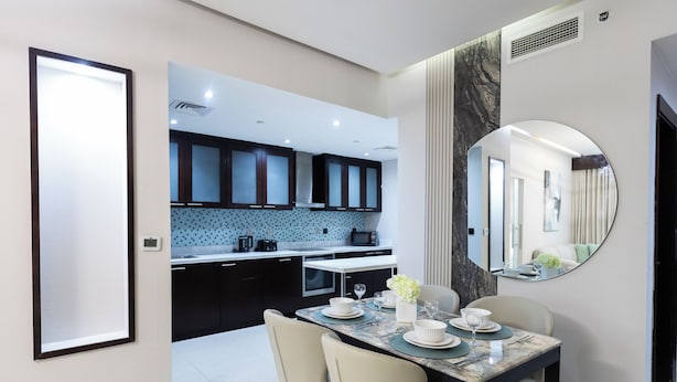 A modern dining area with a marble table, white chairs, and a large mirror on the wall. - Stylish 2BR Business Bay Pool Access (Dubai)