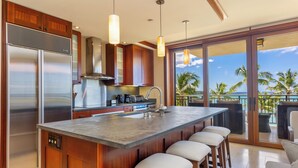 Una cocina moderna con una isla grande, electrodomésticos de acero inoxidable y vistas al océano.